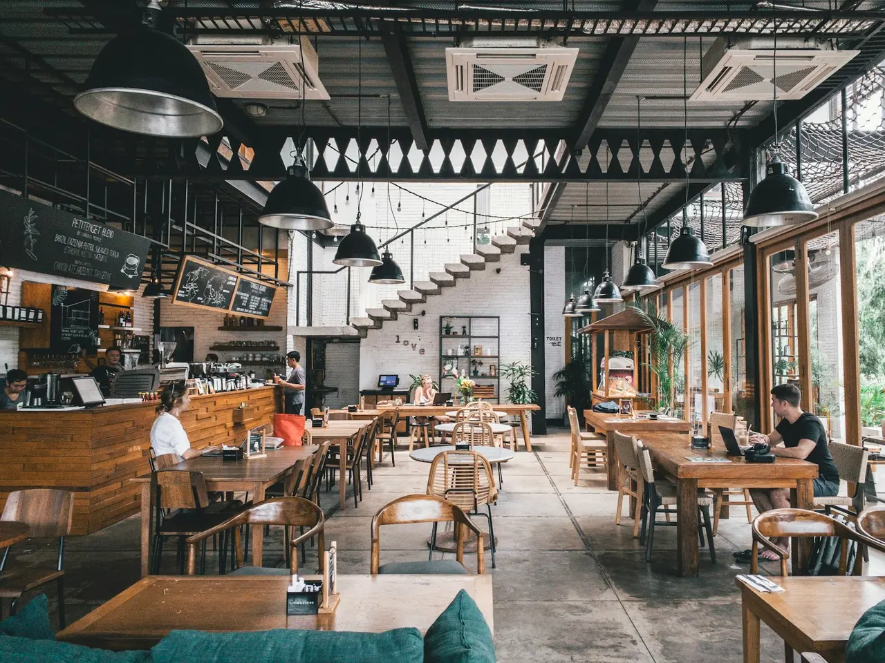 Cafetería amplia con clientes en mesas de madera